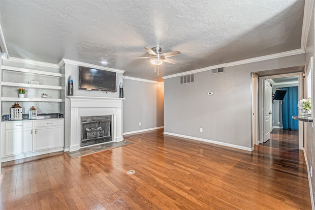 unfurnished living room featuring hardwood / wood-style flooring, a fireplace with flush hearth, visible vents, and a ceiling fan