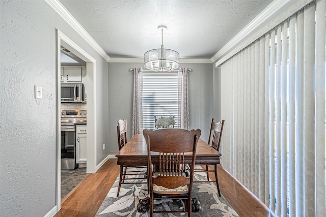 dining room featuring wood-type flooring, a textured ceiling, ornamental molding, and a notable chandelier