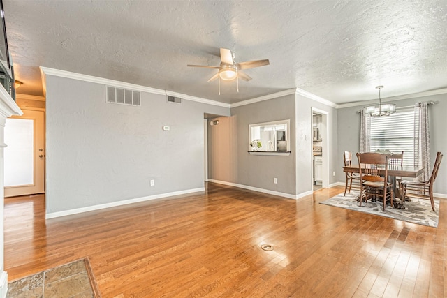 interior space with ceiling fan with notable chandelier, a textured ceiling, hardwood / wood-style flooring, and crown molding