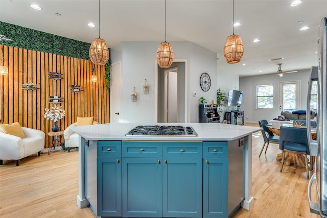 kitchen featuring ceiling fan, hanging light fixtures, blue cabinets, stainless steel gas stovetop, and light wood-type flooring