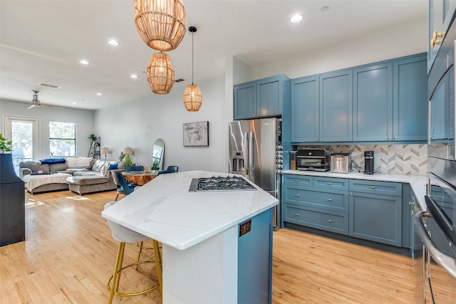 kitchen with blue cabinetry, decorative light fixtures, a center island, and decorative backsplash