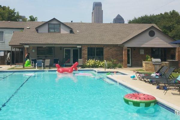 back of house with roof with shingles, area for grilling, a patio area, and a community pool