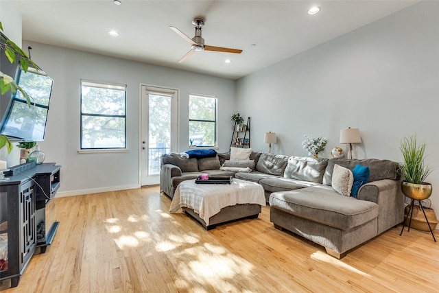 living room featuring light hardwood / wood-style floors, ceiling fan, and a wood stove