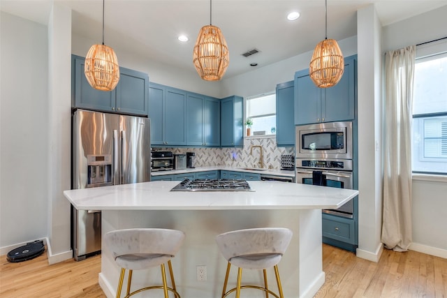 kitchen with a kitchen bar, a kitchen island, appliances with stainless steel finishes, and blue cabinets