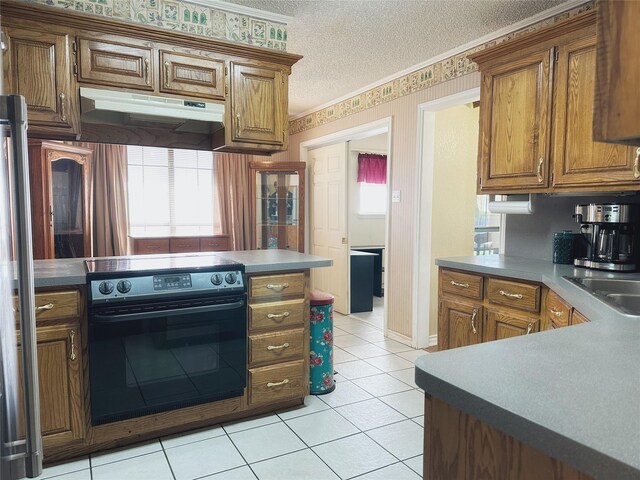 kitchen featuring black range with electric stovetop, sink, ornamental molding, a textured ceiling, and light tile patterned flooring