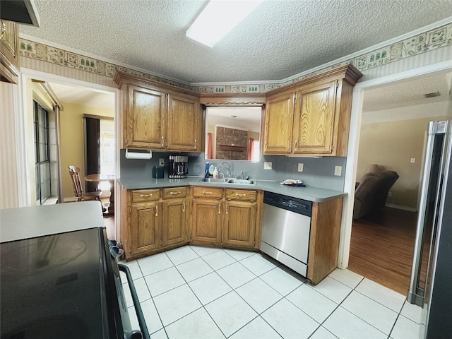 kitchen with appliances with stainless steel finishes, a textured ceiling, light tile patterned floors, and sink