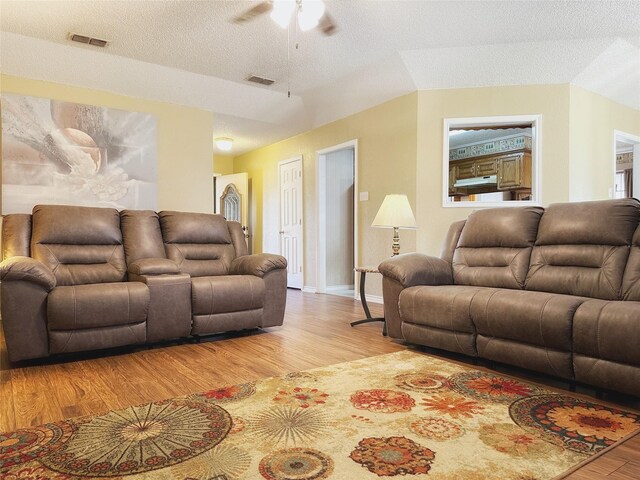 living room with ceiling fan, light hardwood / wood-style flooring, and a textured ceiling