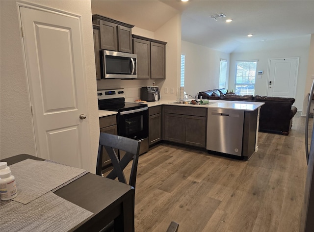 kitchen featuring sink, light hardwood / wood-style flooring, appliances with stainless steel finishes, dark brown cabinets, and kitchen peninsula