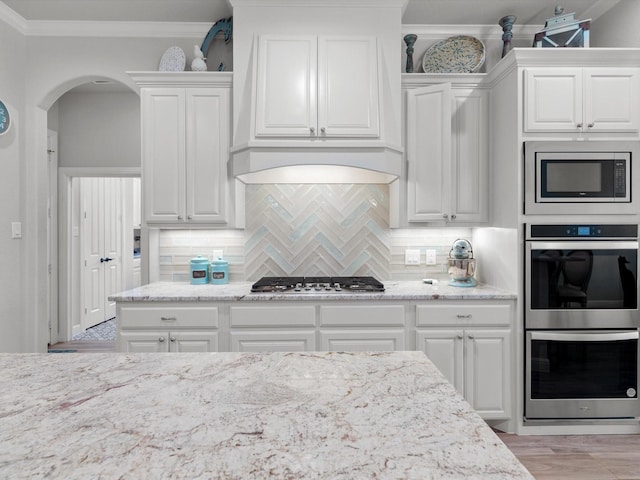 kitchen featuring white cabinetry, ornamental molding, stainless steel appliances, and decorative backsplash