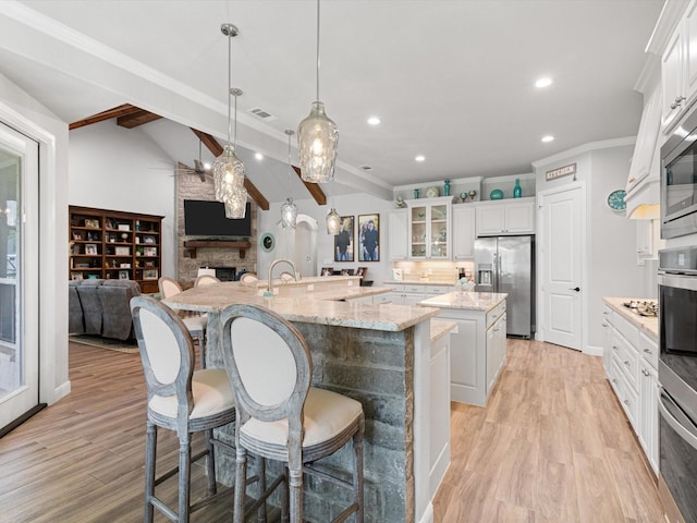 kitchen featuring a large island with sink, stainless steel refrigerator with ice dispenser, pendant lighting, and white cabinets