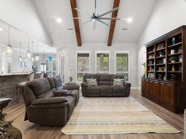 living room with ceiling fan, a wealth of natural light, beamed ceiling, and light wood-type flooring