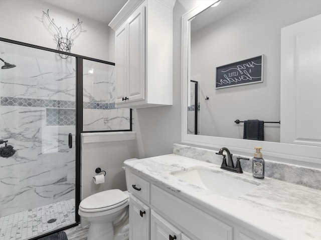 bathroom featuring vanity, a shower with shower door, and toilet