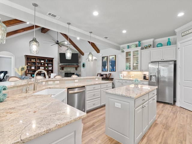 kitchen with white cabinetry, stainless steel appliances, sink, and a kitchen island