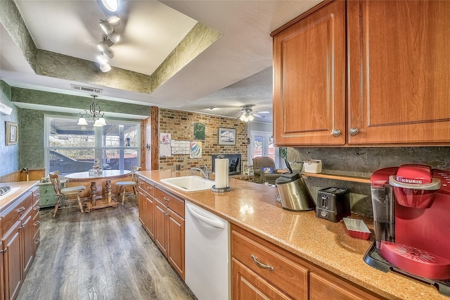 kitchen featuring dishwasher, rail lighting, a raised ceiling, dark hardwood / wood-style flooring, and pendant lighting