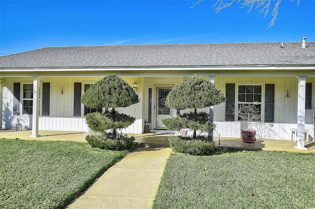 entrance to property featuring a yard and covered porch