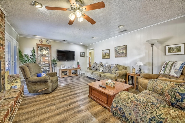 living room featuring a textured ceiling, ceiling fan, and crown molding