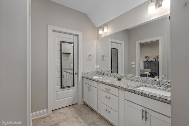 bathroom featuring tile patterned flooring, vaulted ceiling, and vanity