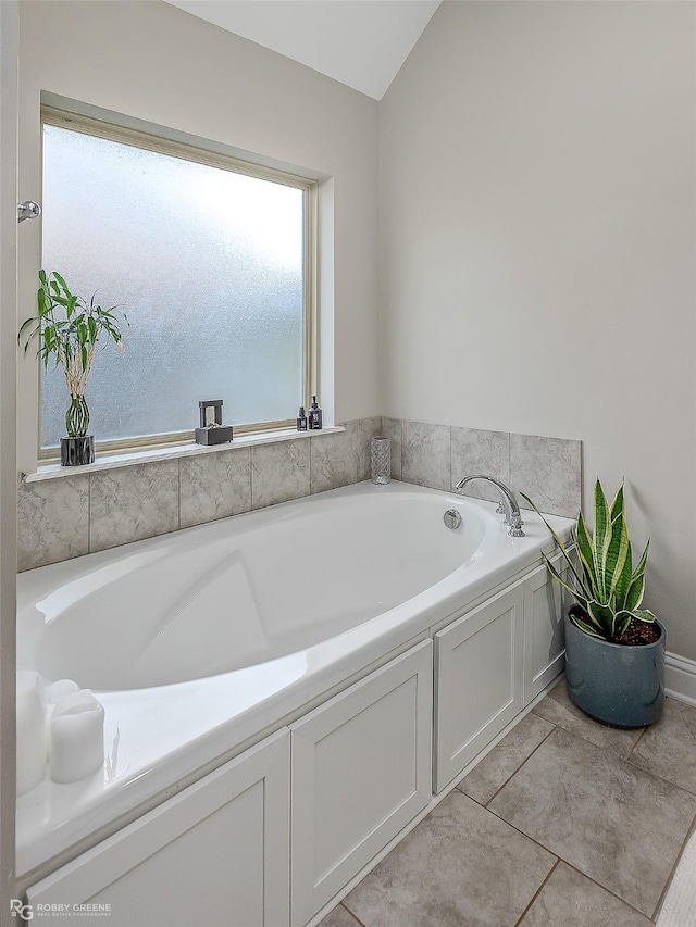 bathroom featuring lofted ceiling and a tub to relax in