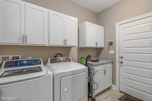 laundry room featuring light tile patterned floors, washer and clothes dryer, and cabinets