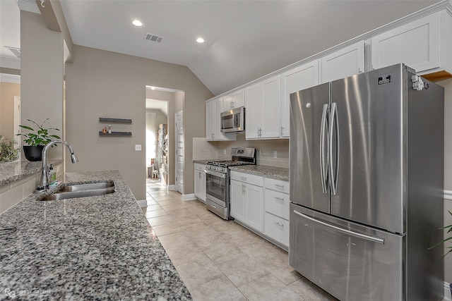 kitchen with white cabinetry, stainless steel appliances, sink, and light stone counters