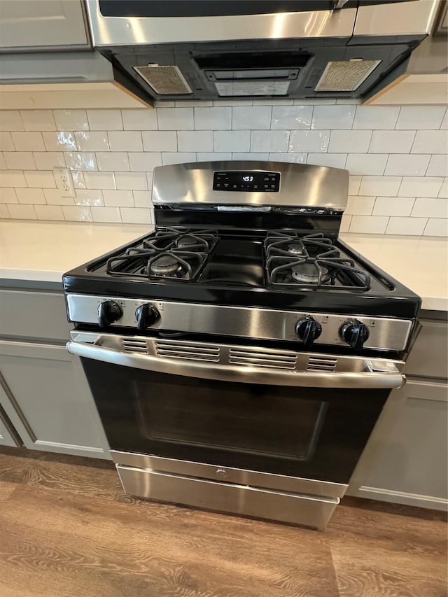 details featuring gas stove, gray cabinets, tasteful backsplash, and hardwood / wood-style floors