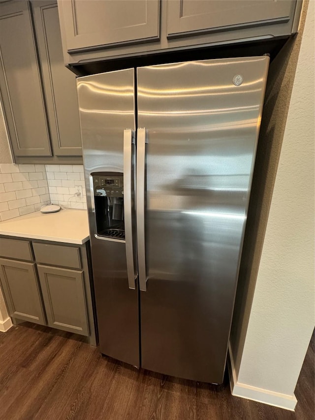 kitchen featuring dark hardwood / wood-style floors, gray cabinets, stainless steel fridge with ice dispenser, and backsplash