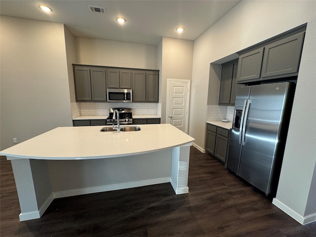 kitchen with appliances with stainless steel finishes, dark hardwood / wood-style flooring, a center island with sink, and sink