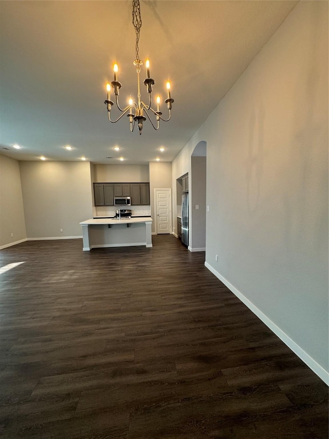 unfurnished living room featuring a chandelier and dark hardwood / wood-style floors