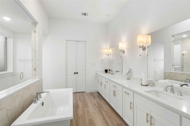 bathroom with plus walk in shower, wood-type flooring, and vanity