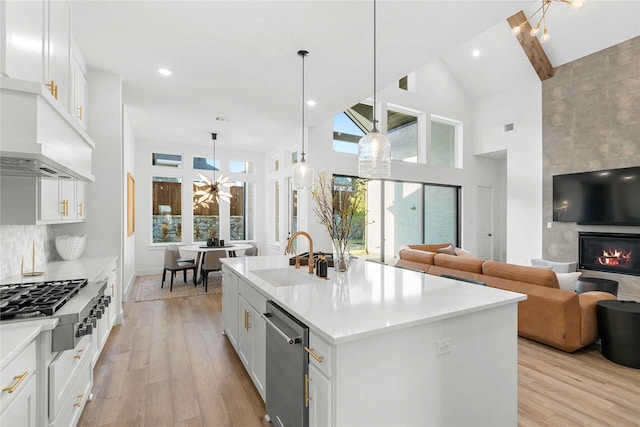 kitchen featuring white cabinets, sink, an island with sink, and pendant lighting