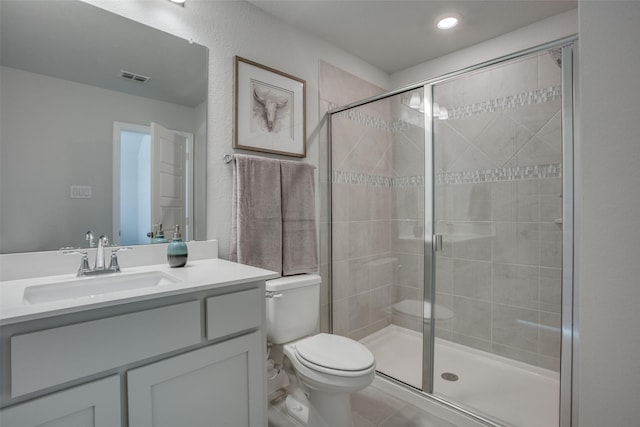 bathroom featuring vanity, tile patterned flooring, a shower with shower door, and toilet