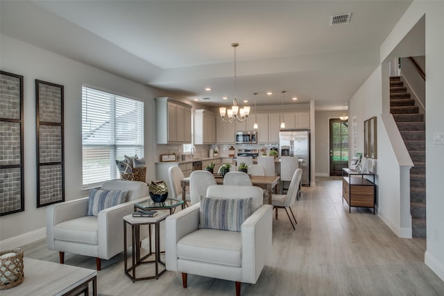 living room with an inviting chandelier, sink, and light hardwood / wood-style floors