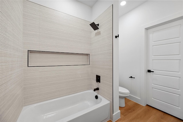 bathroom featuring hardwood / wood-style floors, tiled shower / bath combo, and toilet