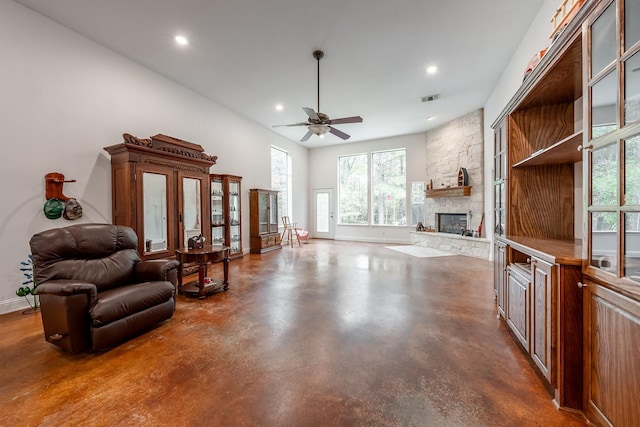 living room featuring ceiling fan and a stone fireplace