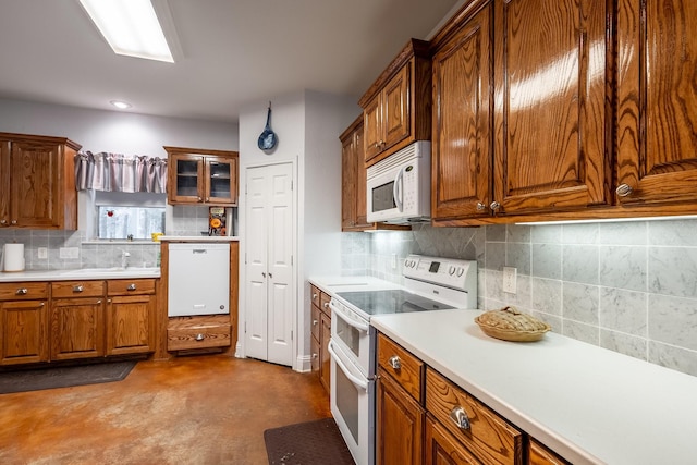 kitchen featuring concrete flooring, decorative backsplash, white appliances, and sink