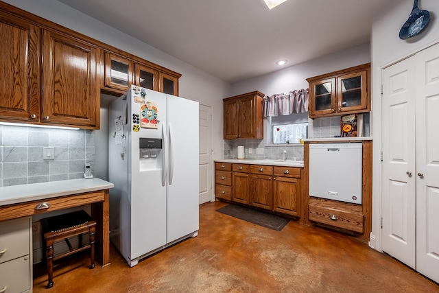 kitchen with tasteful backsplash, sink, concrete floors, and white appliances