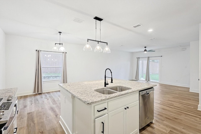 kitchen with white cabinets, dishwasher, an island with sink, open floor plan, and a sink