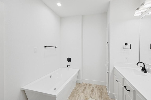 bathroom with hardwood / wood-style flooring, vanity, and a bath