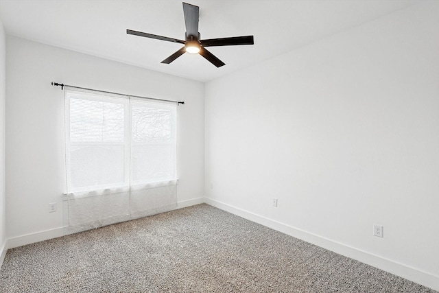 carpeted empty room featuring baseboards and a ceiling fan