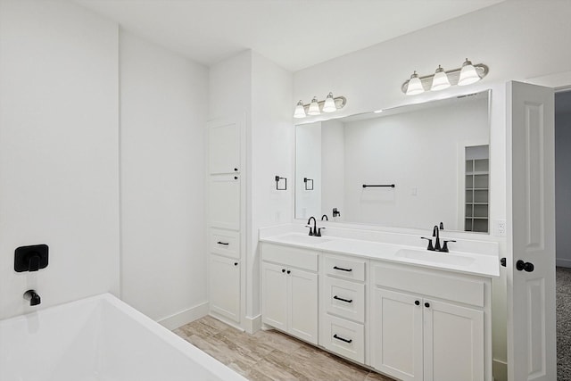 bathroom with hardwood / wood-style floors, a washtub, and vanity