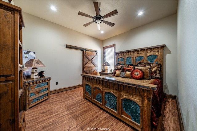 bedroom featuring ceiling fan, wood-type flooring, and a barn door