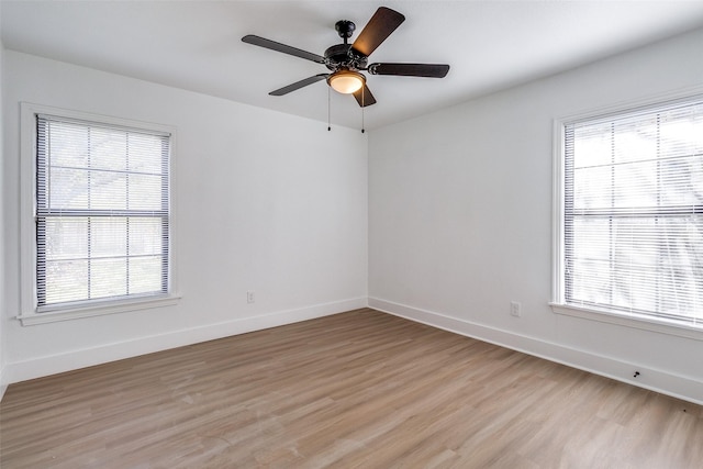 empty room with a wealth of natural light, light hardwood / wood-style floors, and ceiling fan