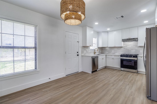 kitchen featuring backsplash, sink, light wood-type flooring, appliances with stainless steel finishes, and white cabinetry