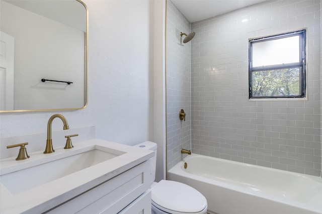 full bathroom featuring vanity, tiled shower / bath, and toilet