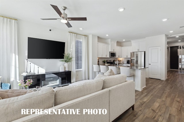 living room featuring ceiling fan and dark wood-type flooring