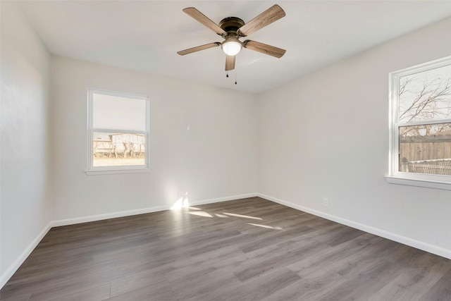 empty room with plenty of natural light, ceiling fan, and dark hardwood / wood-style flooring