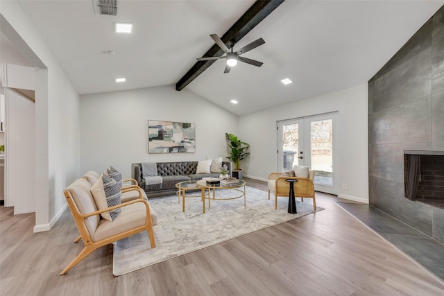 living room featuring light wood-type flooring, french doors, a tiled fireplace, ceiling fan, and lofted ceiling with beams