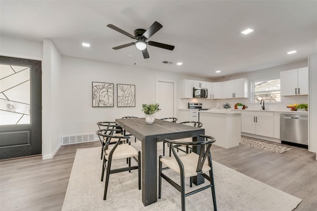 dining room featuring light hardwood / wood-style floors, sink, and ceiling fan