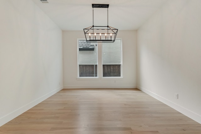 unfurnished dining area featuring a chandelier and light wood-type flooring