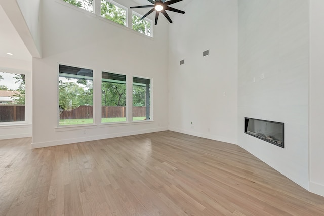 unfurnished living room featuring light hardwood / wood-style floors, a large fireplace, and ceiling fan